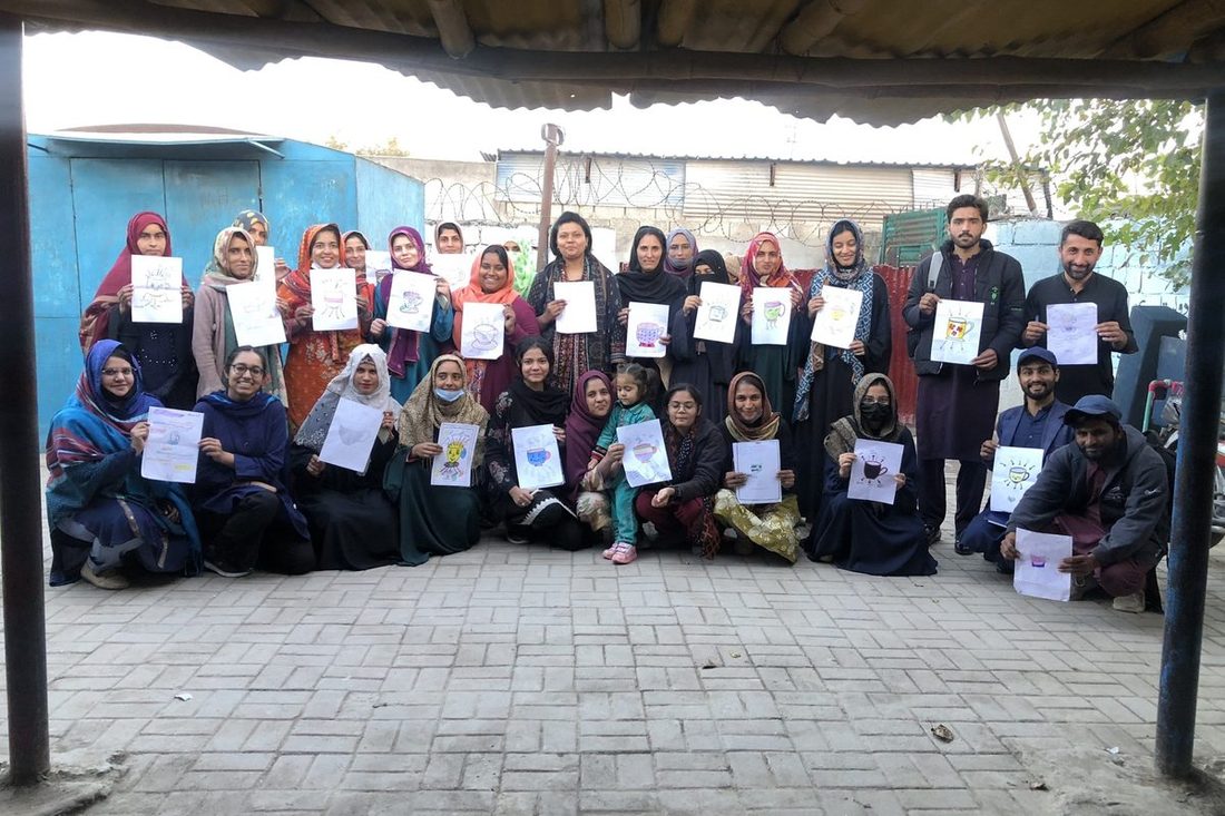 Community workshop participants in Pakistan holding their artwork
